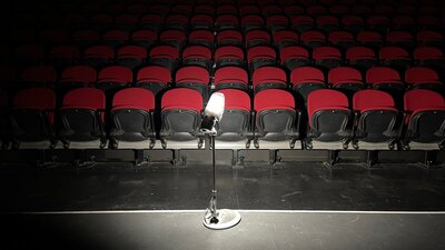 dimly lit image of light on a stand with red theatre seating in background