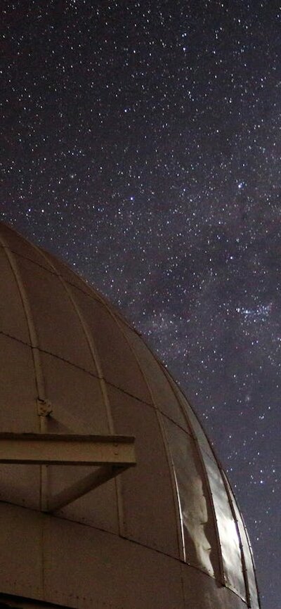 A telescop dome with the Moon and Milky Way Galaxy.