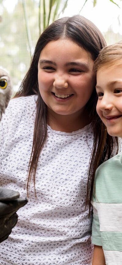 2 Children meeting and handling a barking owl during an encounter at the National Zoo and Aquarium