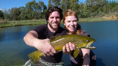 Young couple holding big brown trout