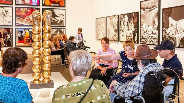 Installation view of Sanné Mestrom, Me & you, 2018 A group of people, some in wheelchairs, sit around a sculpture listening to a guide
