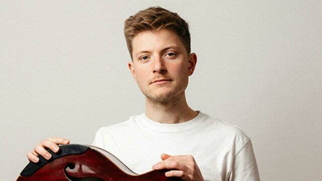 Photo of the artist, Tom Ollendorff Photo of a man sitting holding a jazz guitar