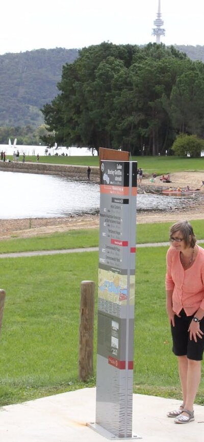 Woman looks at sign on lake edge