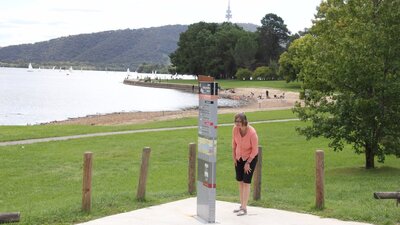 Woman looks at sign on lake edge