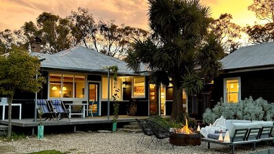 Black house at sunset with firepit in foreground.