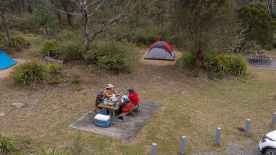 A group of campers eating at the picnic table next to their campsite at Bungonia campground. Photo: