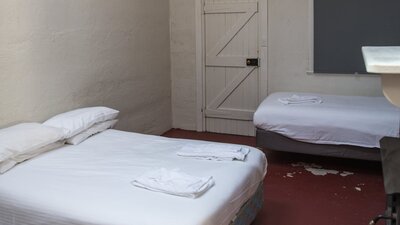 a queen bed and single bed inside the Pisa cottage at Cuppacumbalong