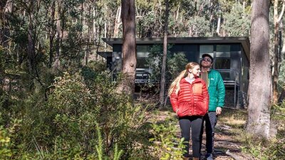 A couple walk through forest near Lyrebird Cottage, Kosciuszko National Park. Photo: Boen