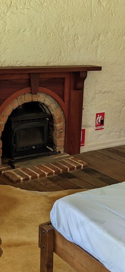 Bedroom with double bed, fireplace, wingback chair and vintage dressing table with mirrors