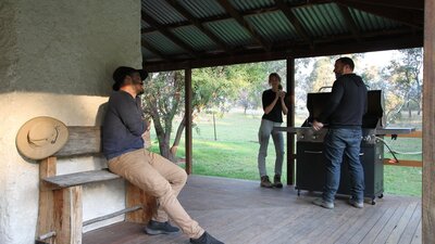 3 people having a BBQ on a verandah