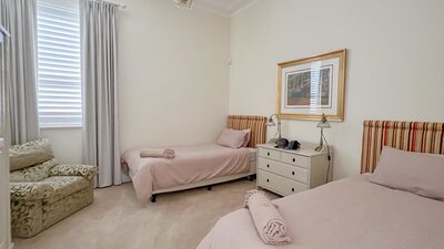 Large bedroom, vintage chair, two king single beds and a bedside table