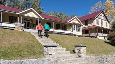 A couple at entry steps to Yarrangobilly Caves House East and West wings, Kosciuszko National Park.