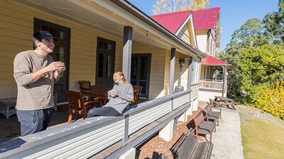 A couple on the verandah at Yarrangobilly Caves House 1901 section, Kosciuszko National Park. Photo: