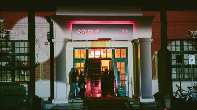 The front facade of the Ainslie Arts Centre, lit up with projected lights and shapes.