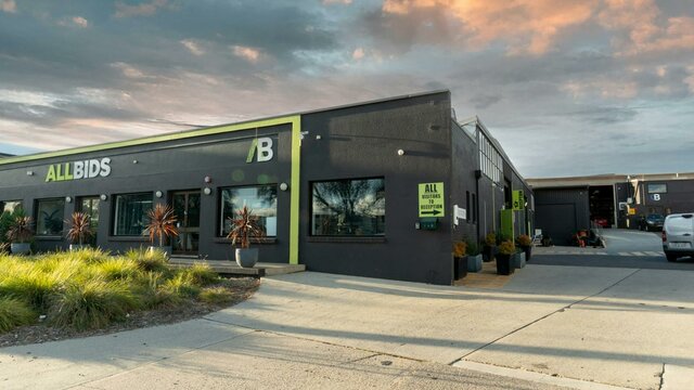 Wide shot of outside of building showing the ALLBIDS and CARBIDS signage