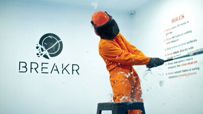 Someone in protective gear, smashing glass with a bat