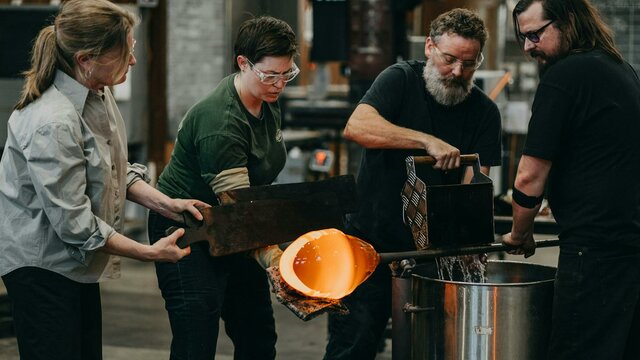 Artists glass blowing in the Hotshop at Canberra Glassworks Four artists cooling the pipes in the Glassowrks Hotshop