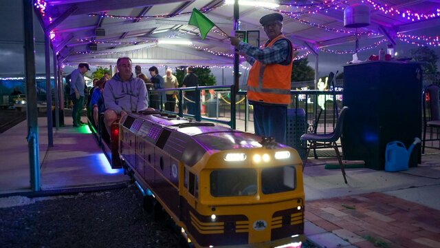 Miniature 422 series train at the station Miniature train at the station under lights with station master signaling to proceed
