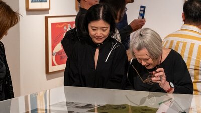 Two women observing objects relating to Cornel & Hiroe Swen's life at Canberra Museum + Gallery