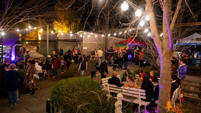 Canberra Potters courtyard at night, with crowds of people and bright coloured and festoon lighting