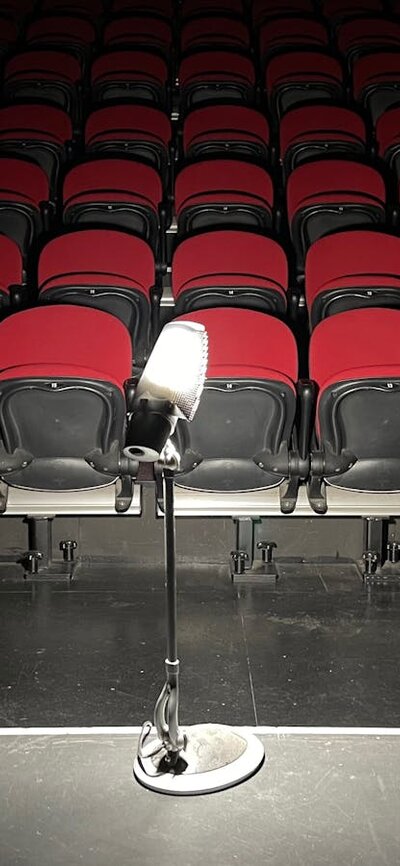 dimly lit image of light on a stand with red theatre seating in background