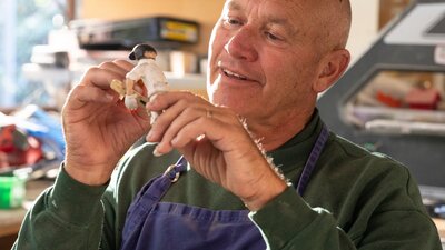 A man creates a small figurine by hand