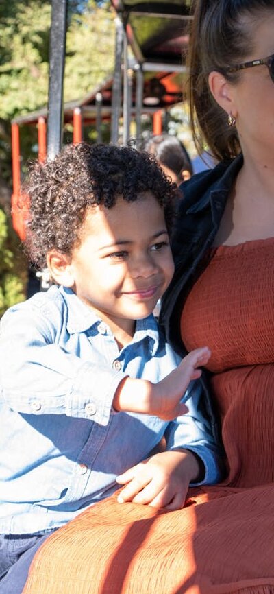 A mother and son ride a steam train and wave to others