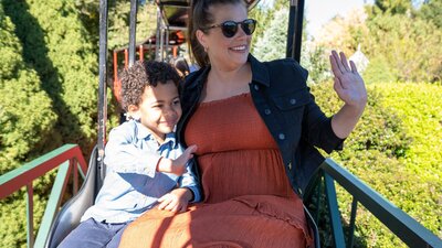 A mother and son ride a steam train and wave to others