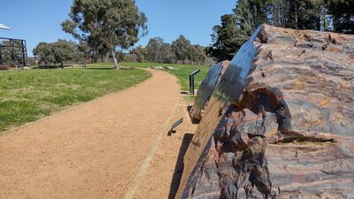 An outdoor gravel path stretches off into the distance. A striped red and black rock is next to it.