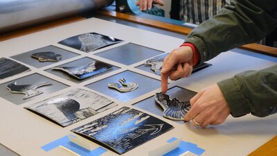 A participant making a final adjustment before printing in a Linocut Masterclass at Megalo