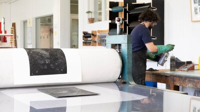 An artist printing an etching on the Hilton etching press at Megalo