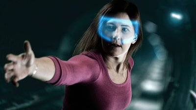 Lady with glowing VR headset reaching out to a camera in escape room