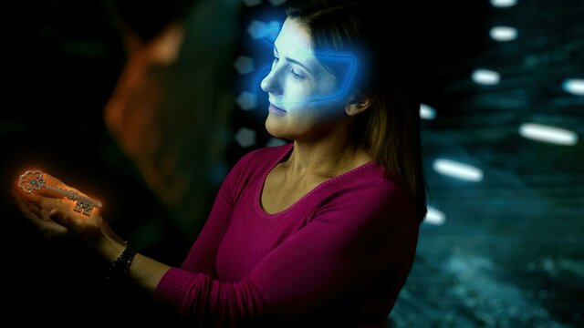 Lady with glowing VR headset looking at glowing key in escape room