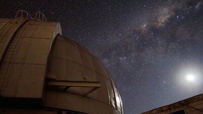 A telescop dome with the Moon and Milky Way Galaxy.