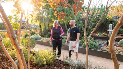 Two people in a garden with autumn leaves and cacti