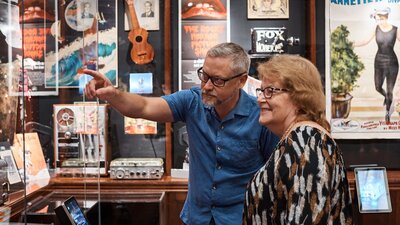 A man and a woman look at artefacts in The Library; the man is pointing something out