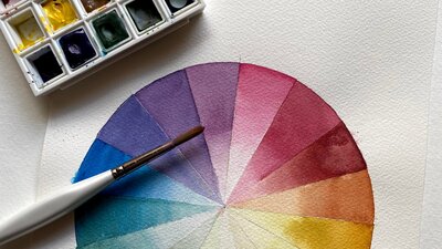 paintbrush and palette sitting on top of a watercolour colour wheel