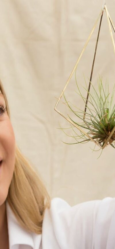 A visitor holding a hanging air plant at the Old Bus Depot Markets