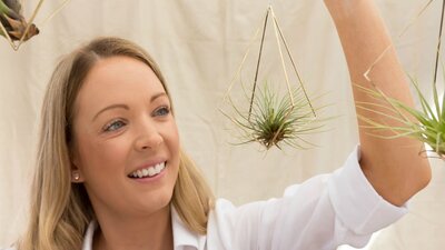 A visitor holding a hanging air plant at the Old Bus Depot Markets