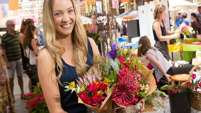 Bunches of fresh native flowers being held by a visitor at the Old Bus Depot Markets