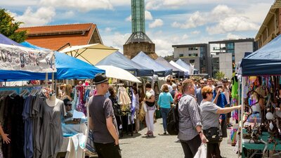 Outdoor stalls and visitors at the front of the Old Bus Depot Markets
