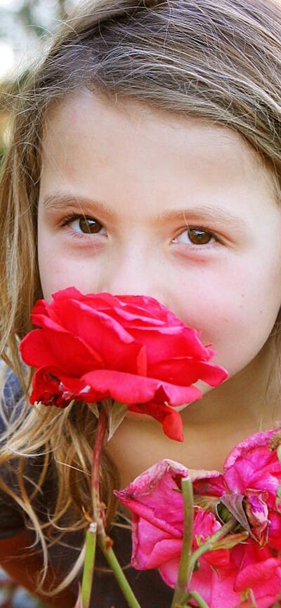 Young girl smelling roses. Photo by Jinkyart