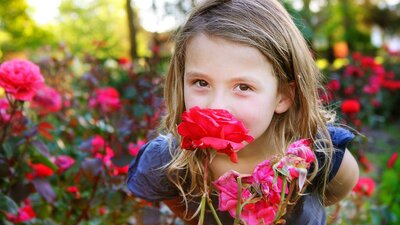 Young girl smelling roses. Photo by Jinkyart