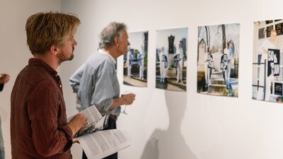 Two men look at photographs on the gallery wall