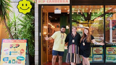 A vibrant storefront of POP Canberra with three smiling staff members outside, promoting local goods