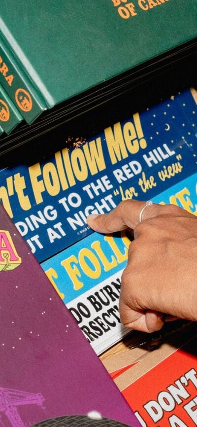 A close-up of a shopper’s hand browsing a selection of Canberra-themed books, stickers