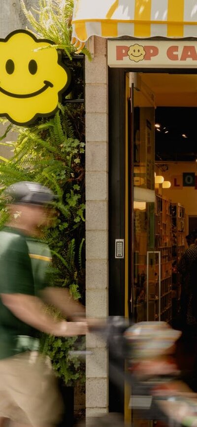 The exterior of POP Canberra, featuring its bright yellow awning, inviting signage, and good vibes.