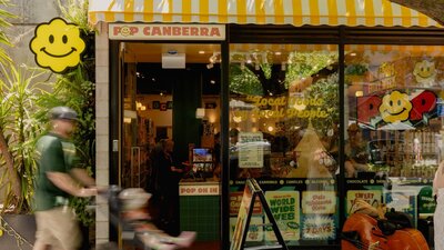 The exterior of POP Canberra, featuring its bright yellow awning, inviting signage, and good vibes.