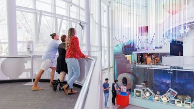 3 young people stand looking at a rainbow exhibit at Questacon