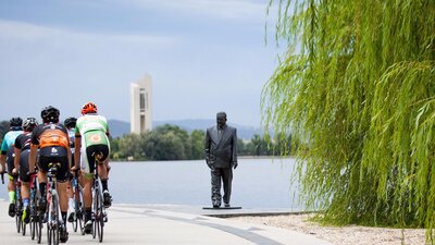 Group of cyclists going past the R G Menzies statue on the Lake Burley Griffin foreshore